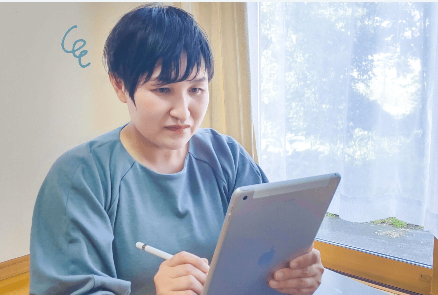 窓辺でiPadを操作しながらノートを取る悠理さん