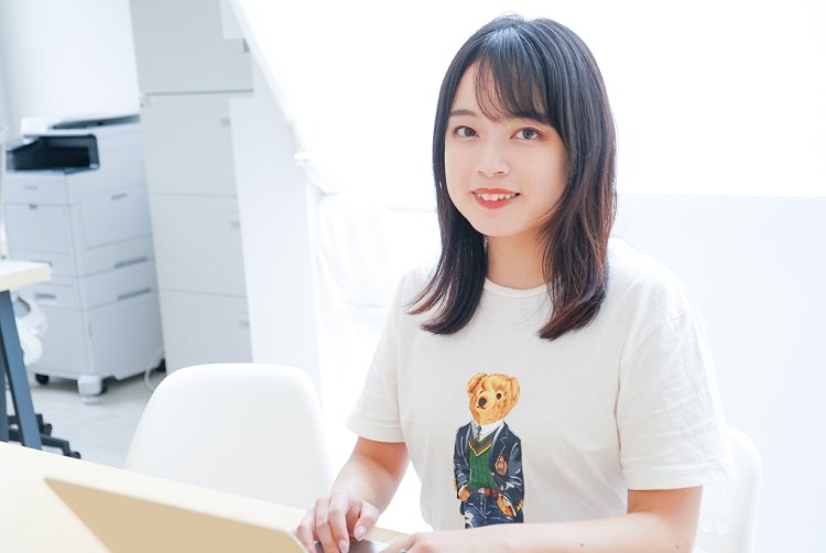 デスクでノートパソコンに手を添えて微笑むいとまりさん