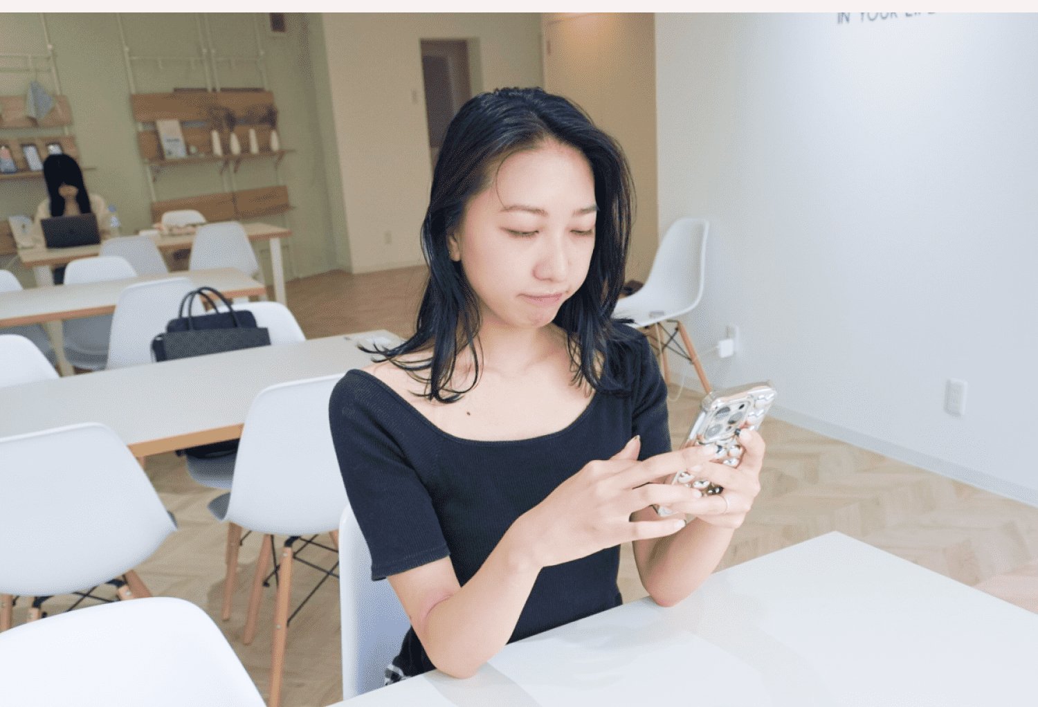 SHElikesの拠点で椅子に座りスマホを見るazuさん
