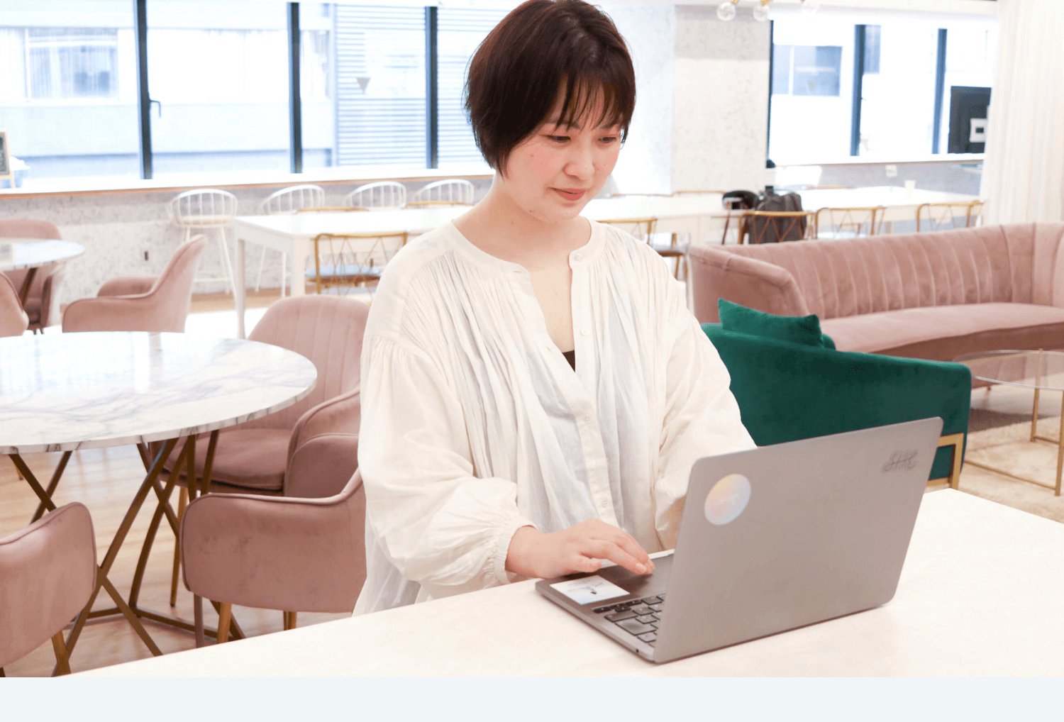 オフィスのカフェスペースでノートPCを操作する女性