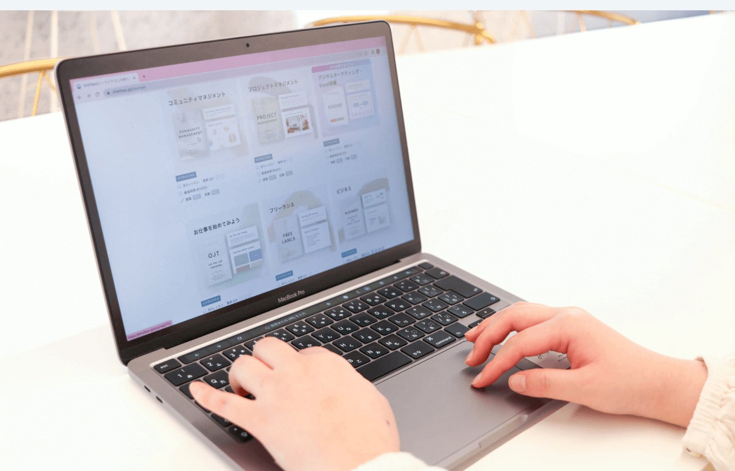 MacBookの画面に映るSHElikesのコース一覧をタイピングする両手