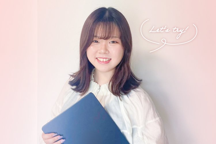 白いフリル付きブラウス姿でノートPCを抱えて微笑むナギさん（「Let's try!」の吹き出し装飾つき）