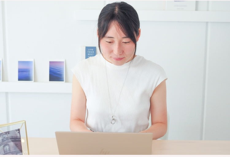 窓際のデスクでノートPCに向かうこじゆかさん