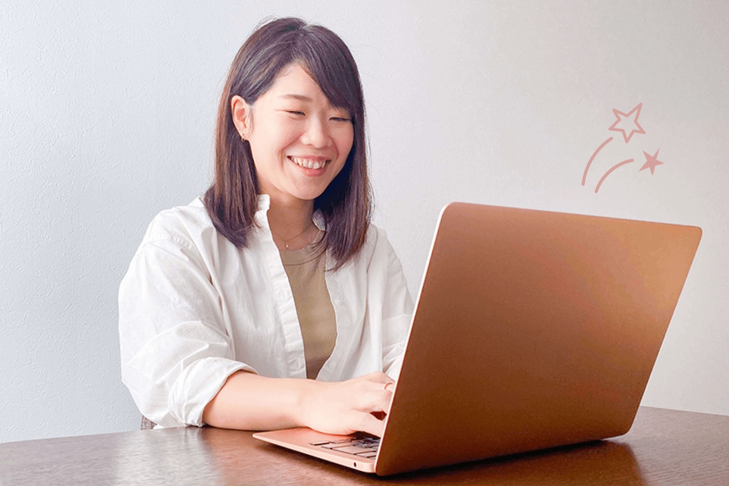 白シャツでノートPCに向かい微笑みながらタイピングするゆみさん