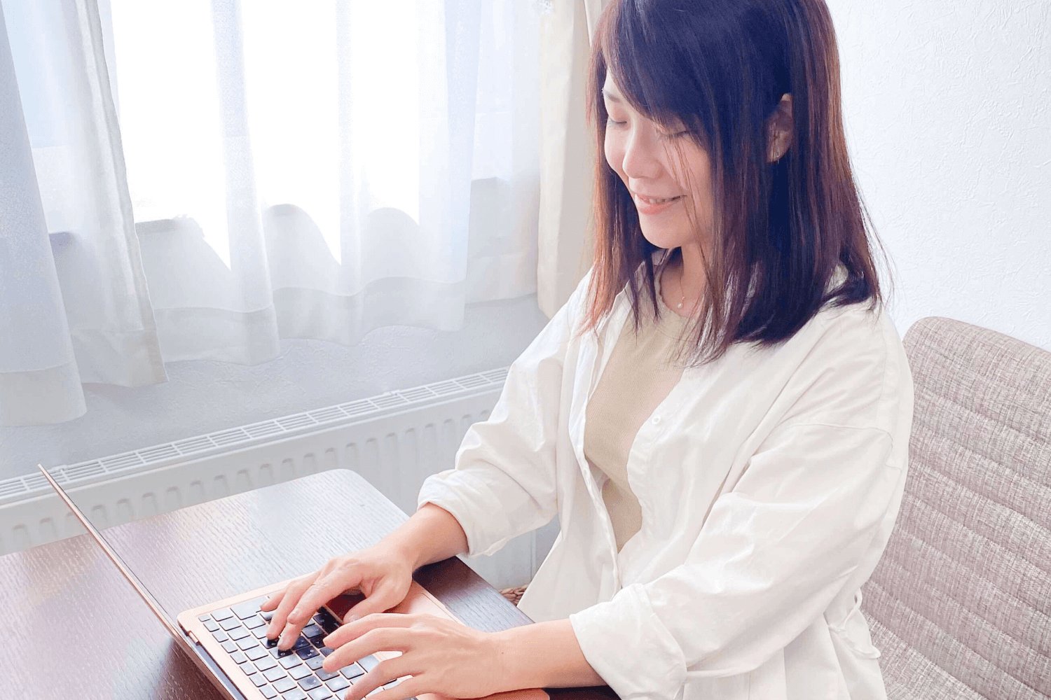 窓際でノートPCに向かい微笑むゆみさんの横顔