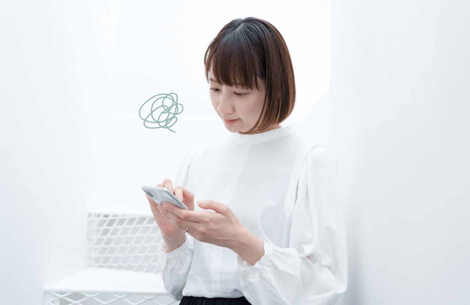 スマホを操作しながら考え込む表情の女性