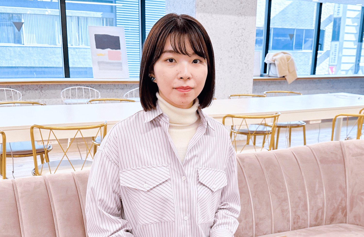 オフィスラウンジのソファに座り微笑む千晴さん