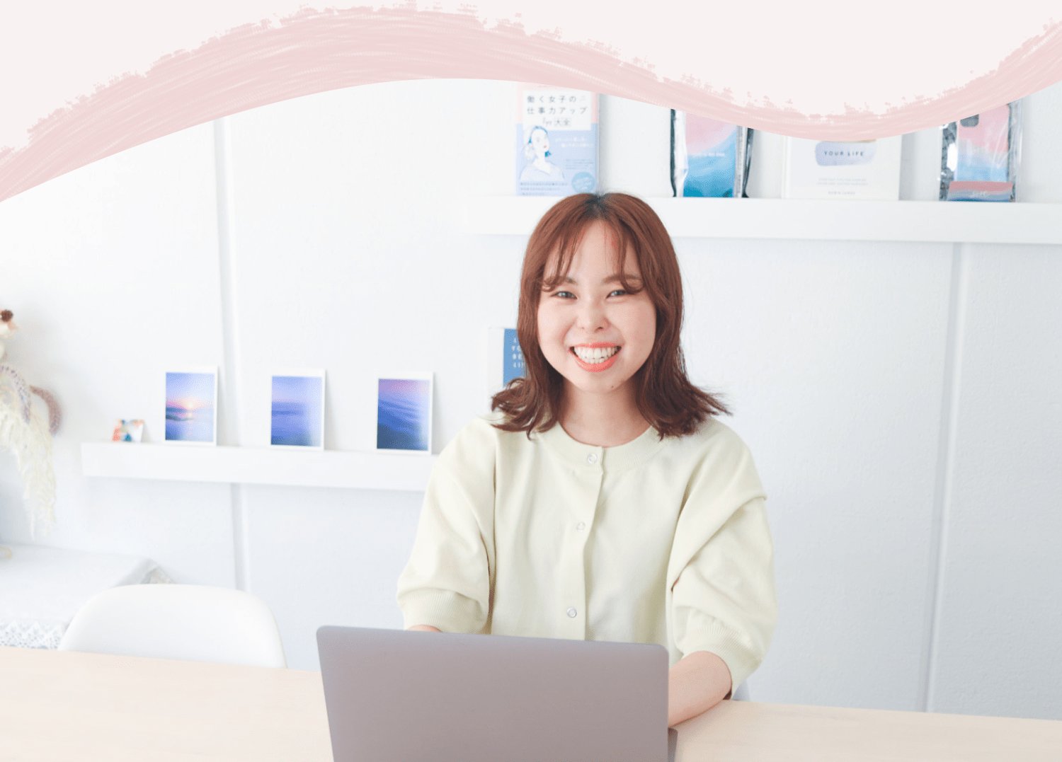 棚の前に座りノートPCを開いて微笑む結風さん