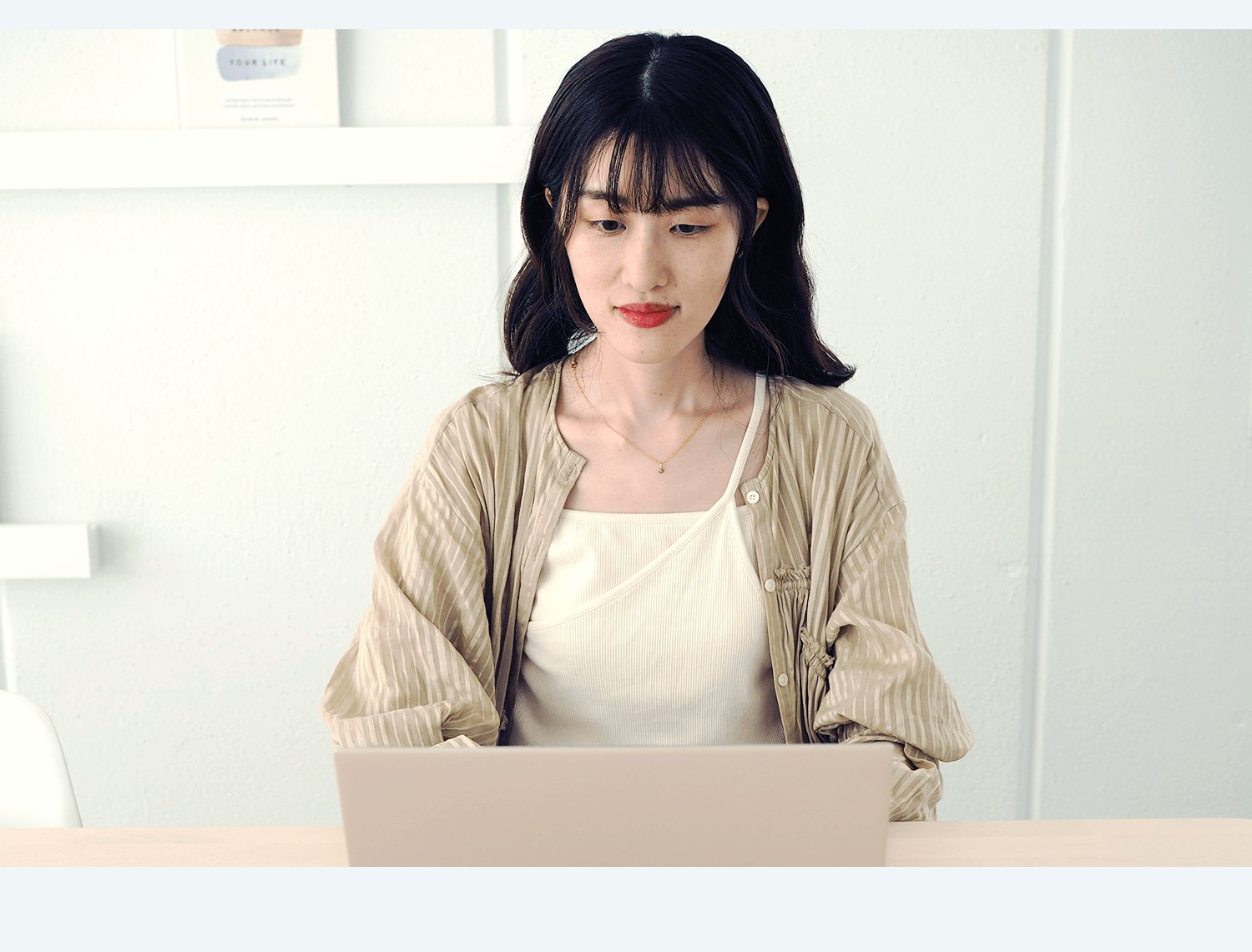棚のある部屋でノートPCに向かって作業するかえさんの写真