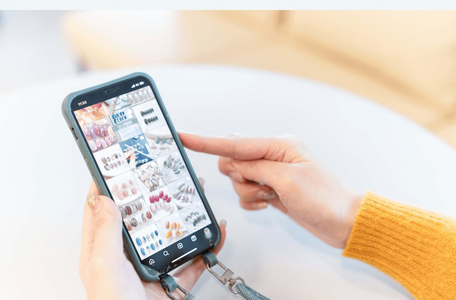 スマホでInstagramのネイル作品ギャラリーを指差し確認するhaluさんの手元