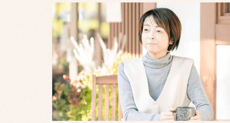 屋外の椅子に座りマグカップを持ち微笑むあやこあにぃさん