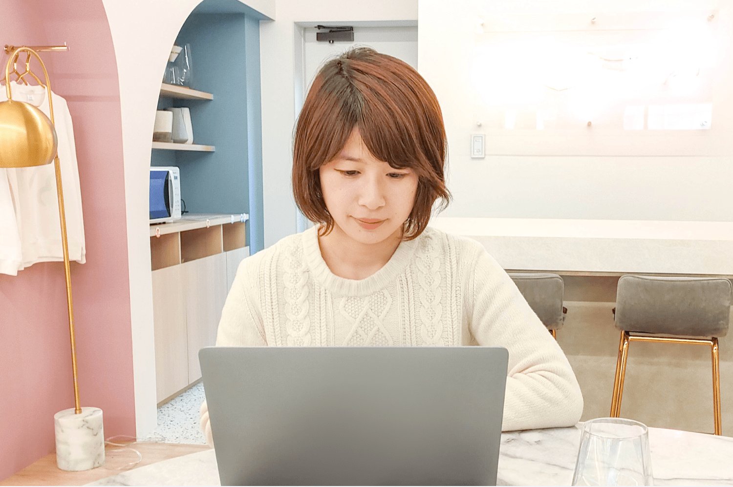 ピンクの壁のあるオフィスでノートPCに向かうぴょすさん