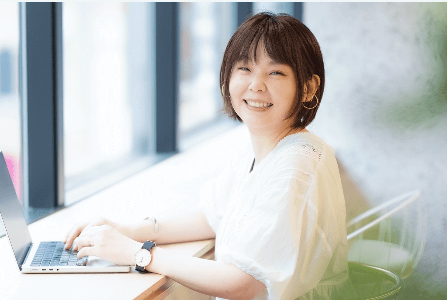 窓際のカウンターでノートPCを操作しながらこちらに微笑みかけるのりさん