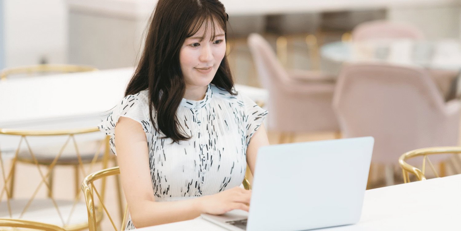 カフェのような空間でノートPCを開くMOEさんのポートレート