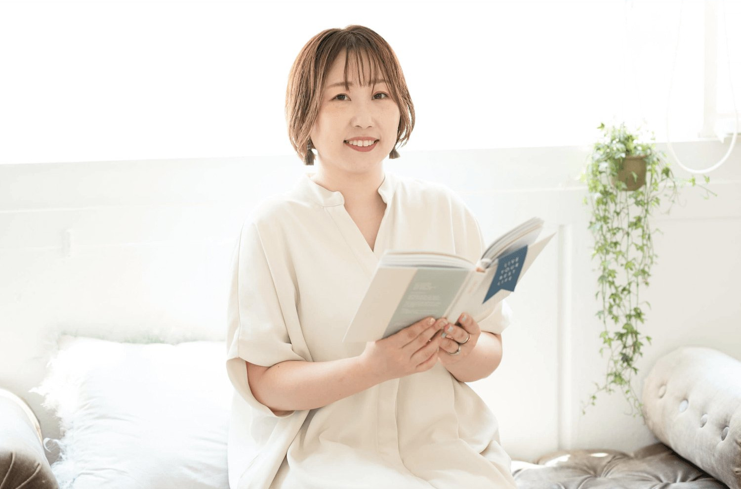 リビングのソファで本を開き、微笑むリエさん