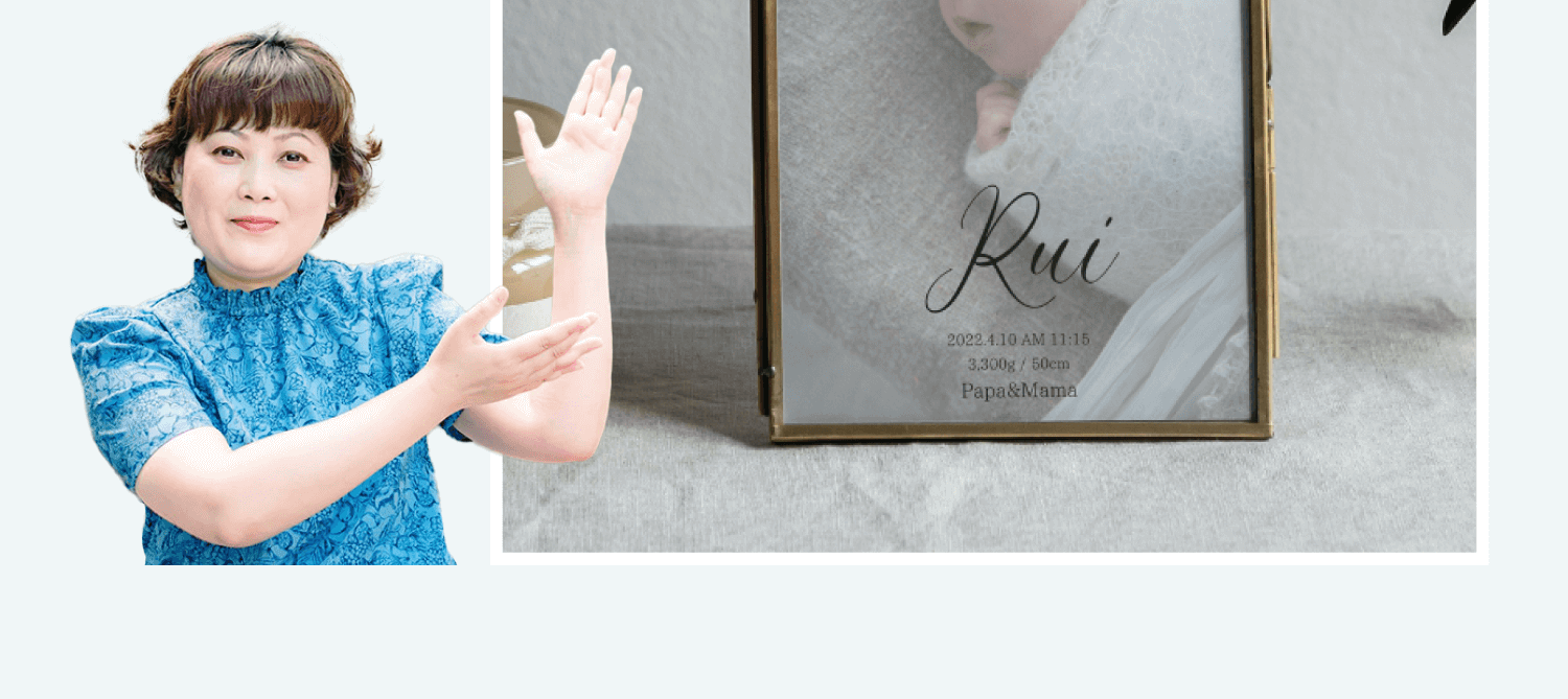 薫さんが完成した命名書「Rui」の写真立てを紹介するカット