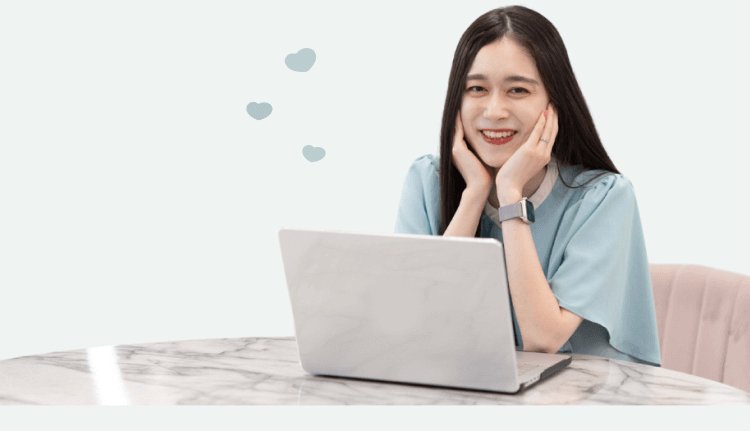 マーブル模様のデスクでノートPCを開き、両手を頬に添えて笑うHinakoさん