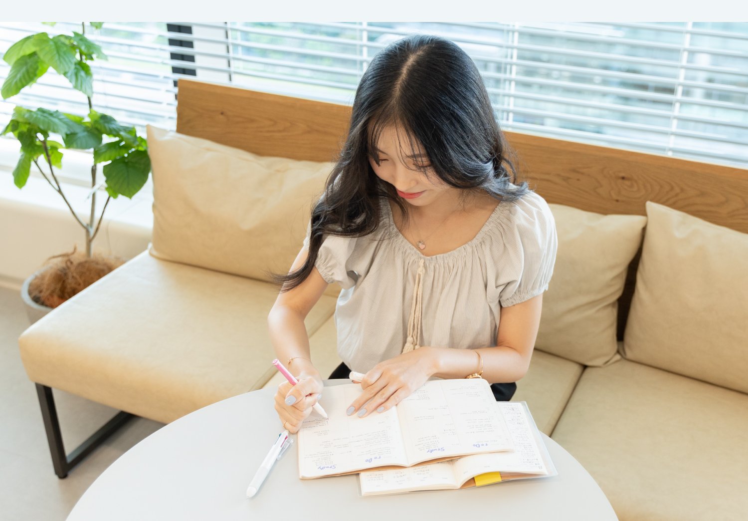 ソファ前のテーブルでノートに書き込みながら企業案件への応募を検討するNabiさん