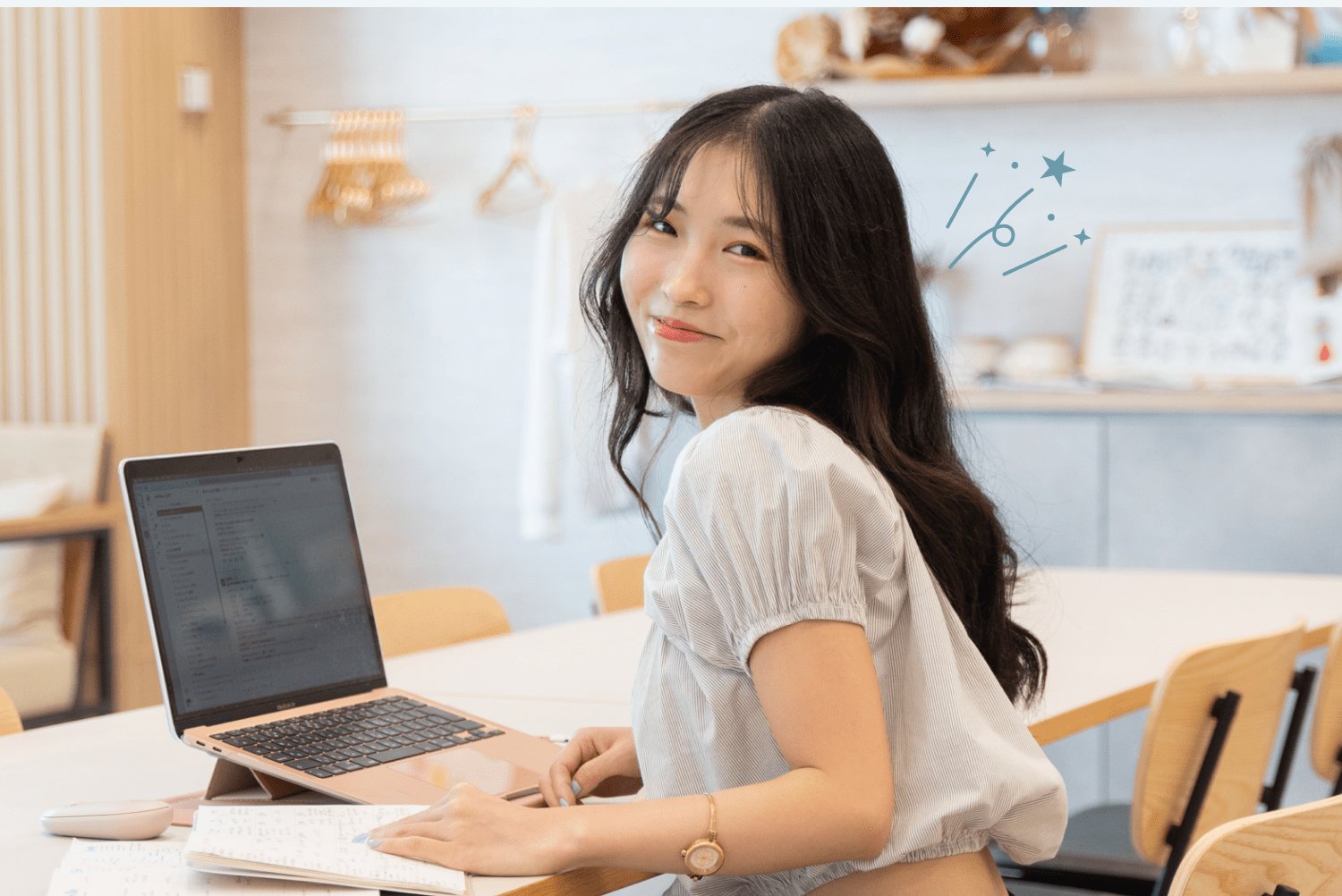 SHE Umedaの拠点で、ノートPCを操作しながら振り返って微笑むNabiさん