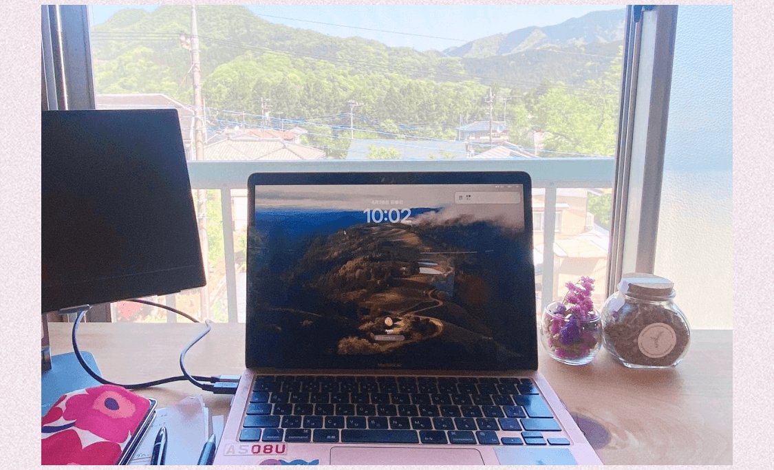 山あいの窓辺に置かれたノートPC。ロック画面に山道の空撮写真、時刻10:02