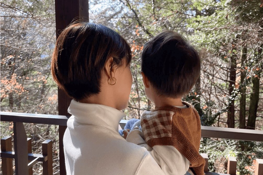山の展望台で息子を抱き、森を眺める後ろ姿のちっひーさん