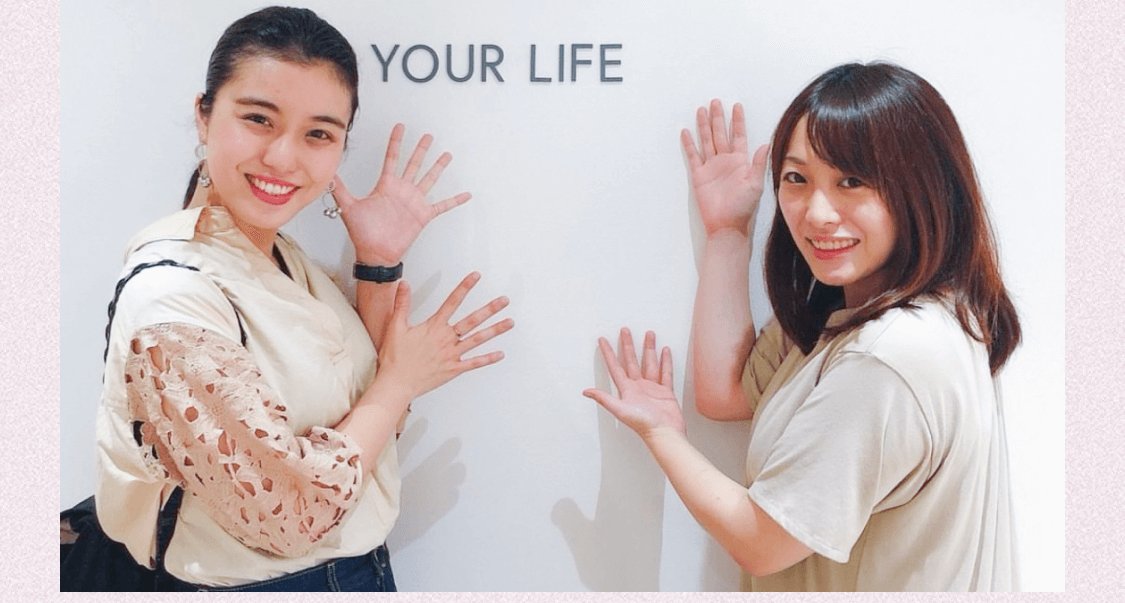 SHElikesのイベントスペースで壁に手をついてポーズを取る杏珠さんとスタッフ(MAKE GRADATION YOUR LIFEの壁文字)
