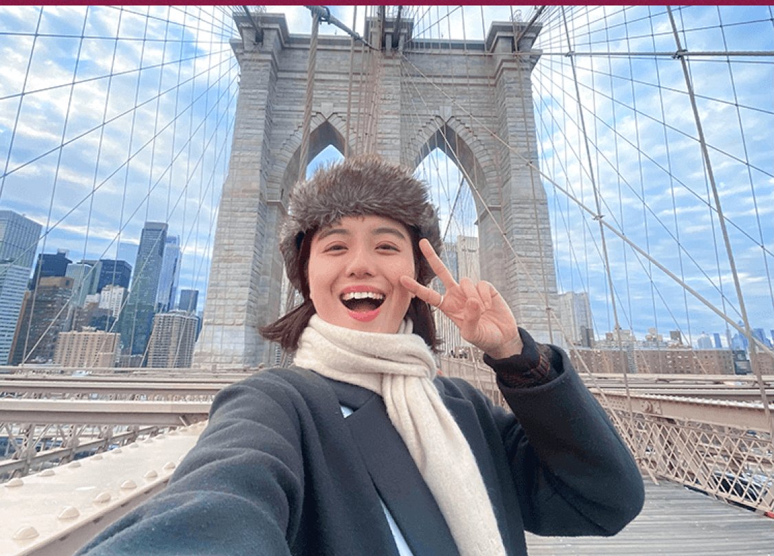 ブルックリン橋の上でピースサインをする杏珠さんのセルフィー(毛皮風帽子・マフラー、NYの摩天楼を背景)