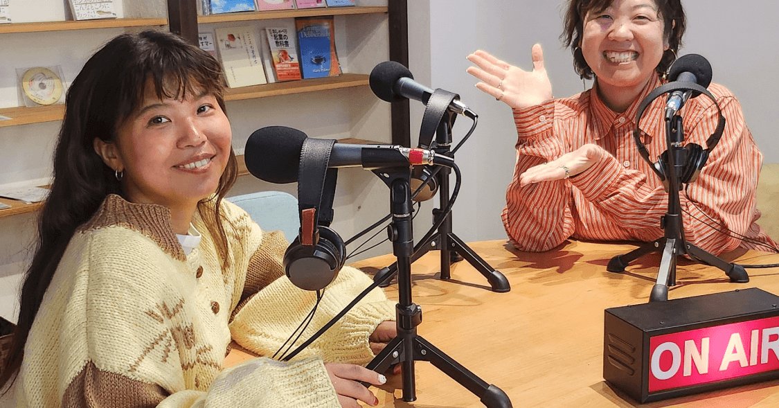 マイクとヘッドホンが並ぶ収録スタジオで、笑顔で話す女性2人(「ON AIR」の看板あり)