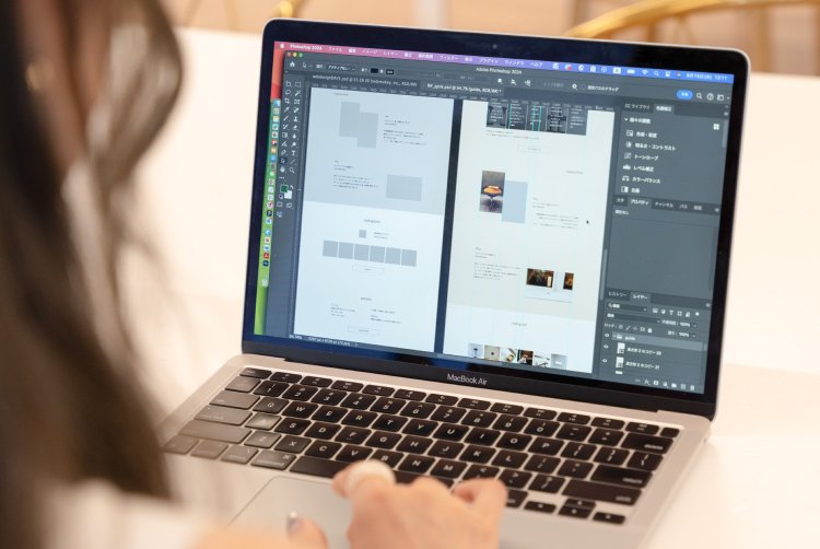 MacBookでPhotoshopを開き、デザイン制作物を編集するさきさんの手元