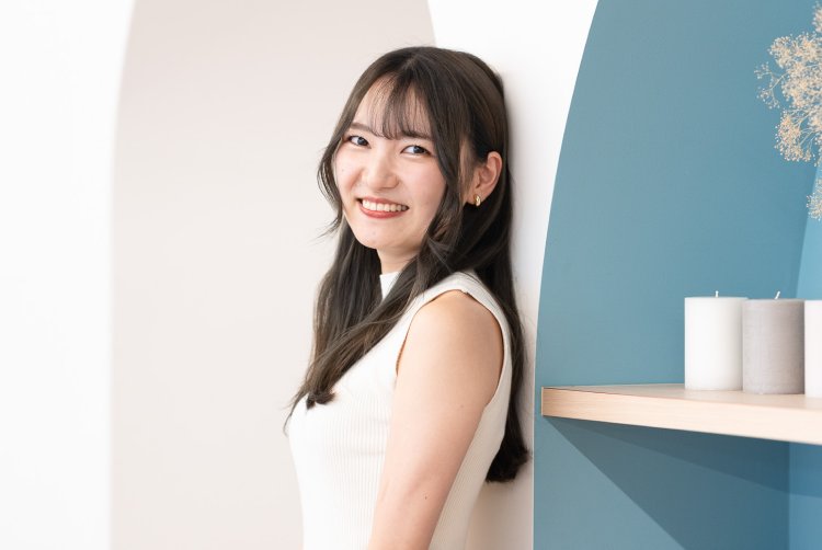 アーチ型の壁を背景に微笑むさきさん