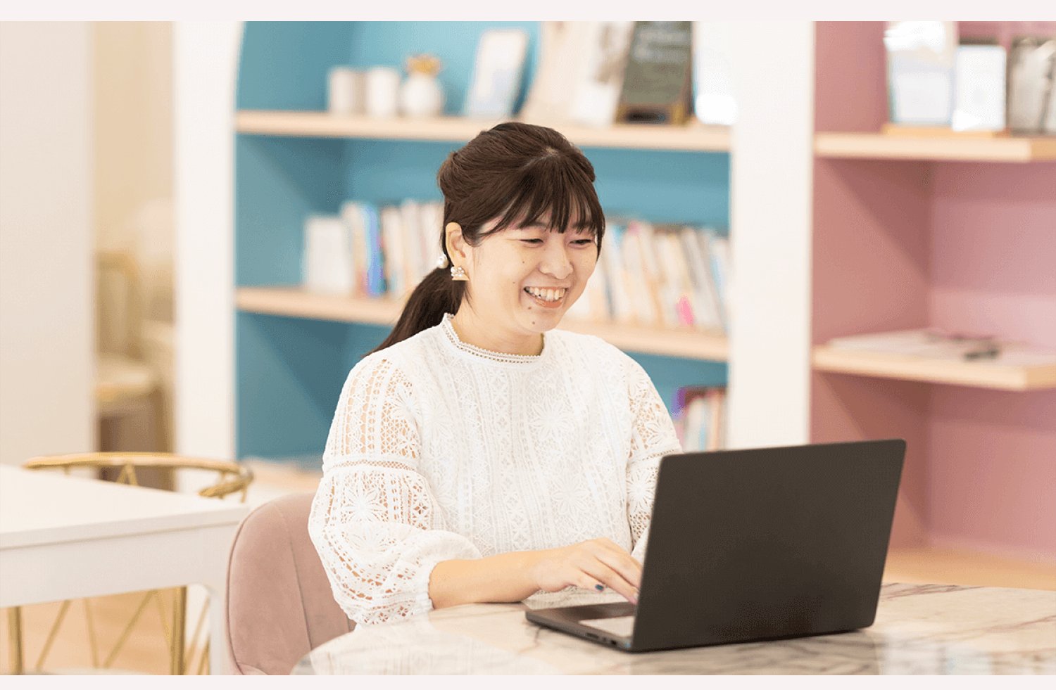 SHElikesのラウンジでノートPCを操作しながら微笑むくみさん