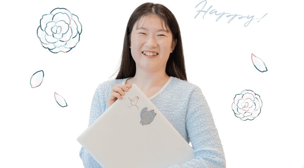 花のイラストに囲まれ、ノートPCを抱えて満面の笑みを見せるもんかさん