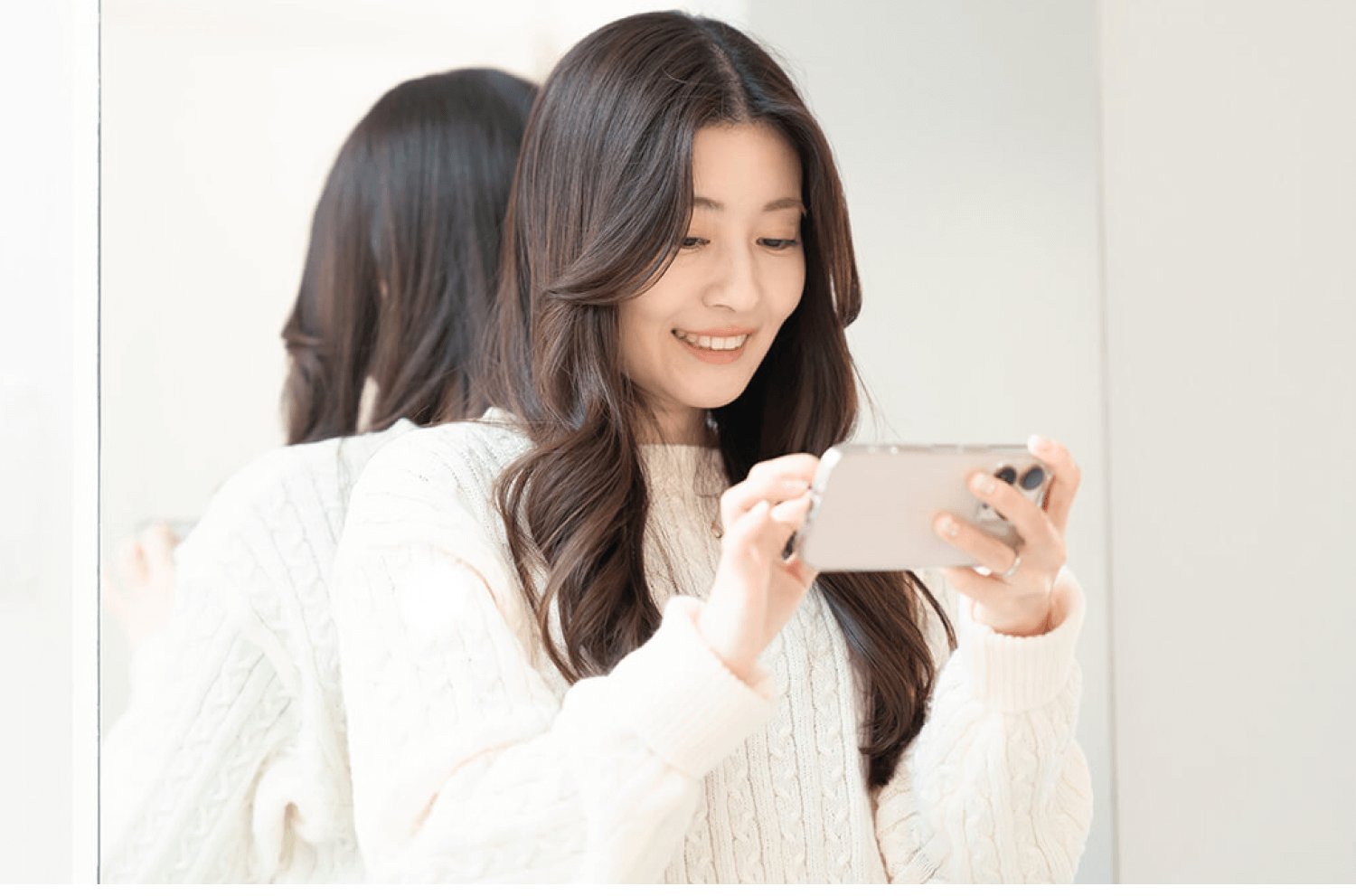 スマートフォンで自撮りをしながら微笑むあやのえるさんの写真