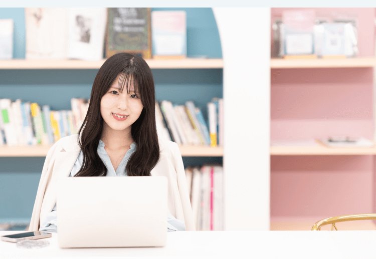 本棚を背景にノートPCに向かうKaorukoさん