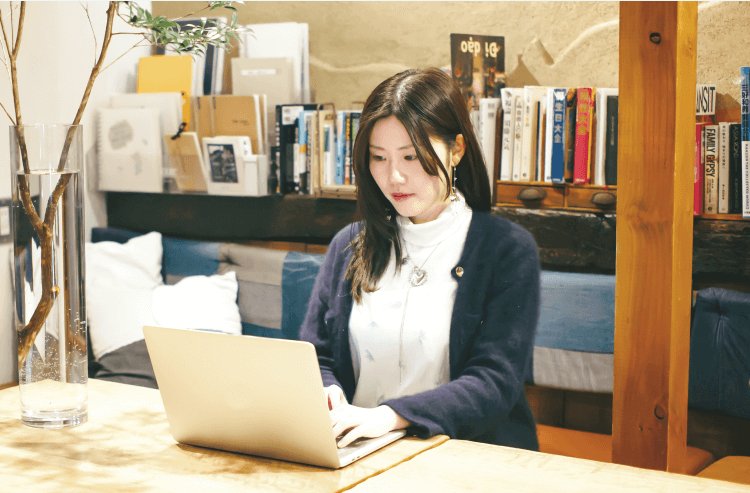 本棚のある室内でノートPCに向かうりささん