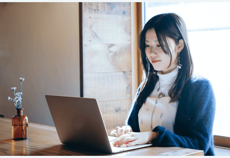 花瓶の花のそばでノートPCに向かうりささん