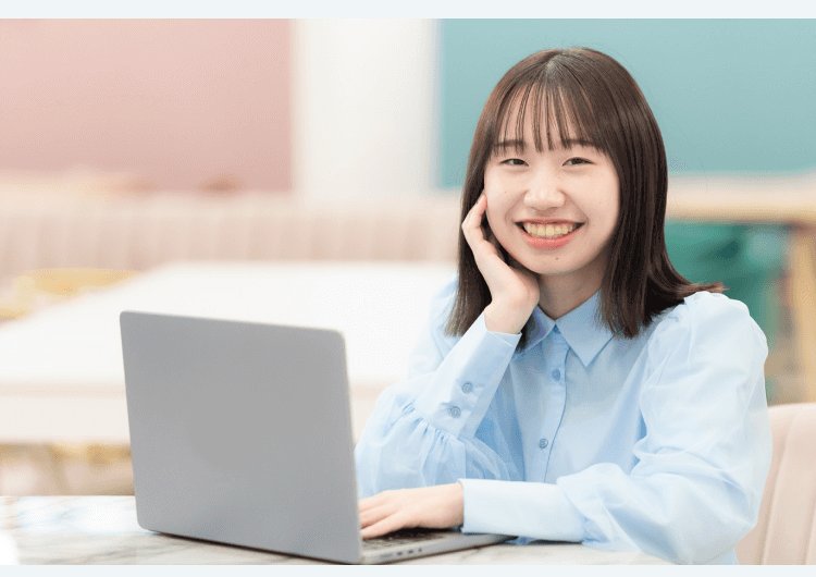 テラス風の室内でノートPCに向かい微笑むHicaさん