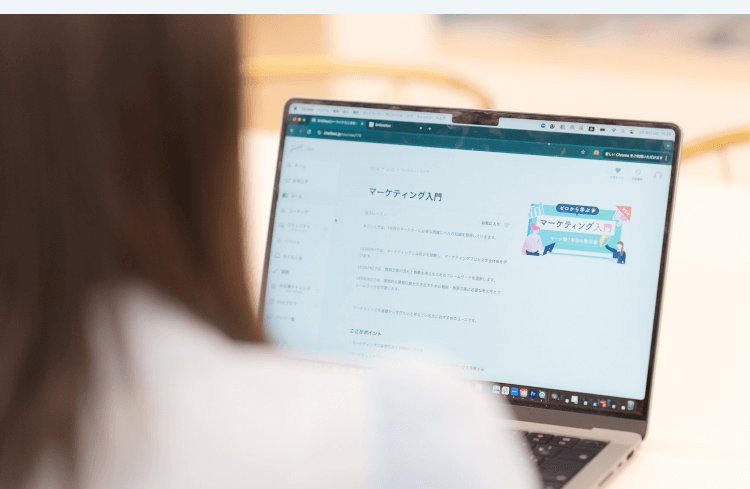 「マーケティング入門」のコース受講画面を肩越しに見つめるHicaさん