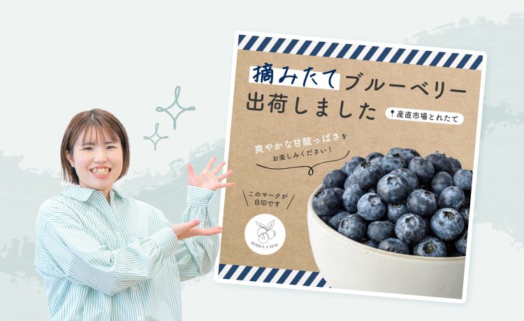 「摘みたてブルーベリー出荷しました」の自主制作バナーデザインを指差して紹介するまほさんの写真