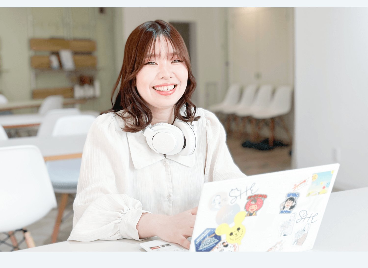 オフィスでヘッドホンを首にかけノートPCに向かい微笑む秋葉みやびさん