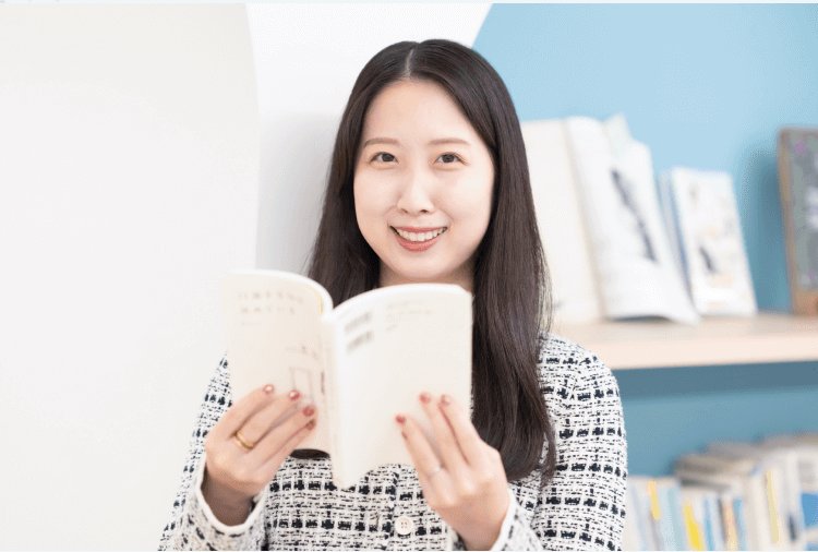 本を開いて読みながら微笑むかんなさん