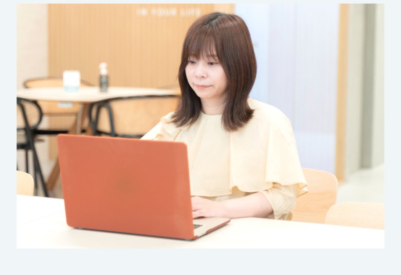 SHElikesのカフェスペースでオレンジ色のノートPCを操作するIKUMIさんの写真