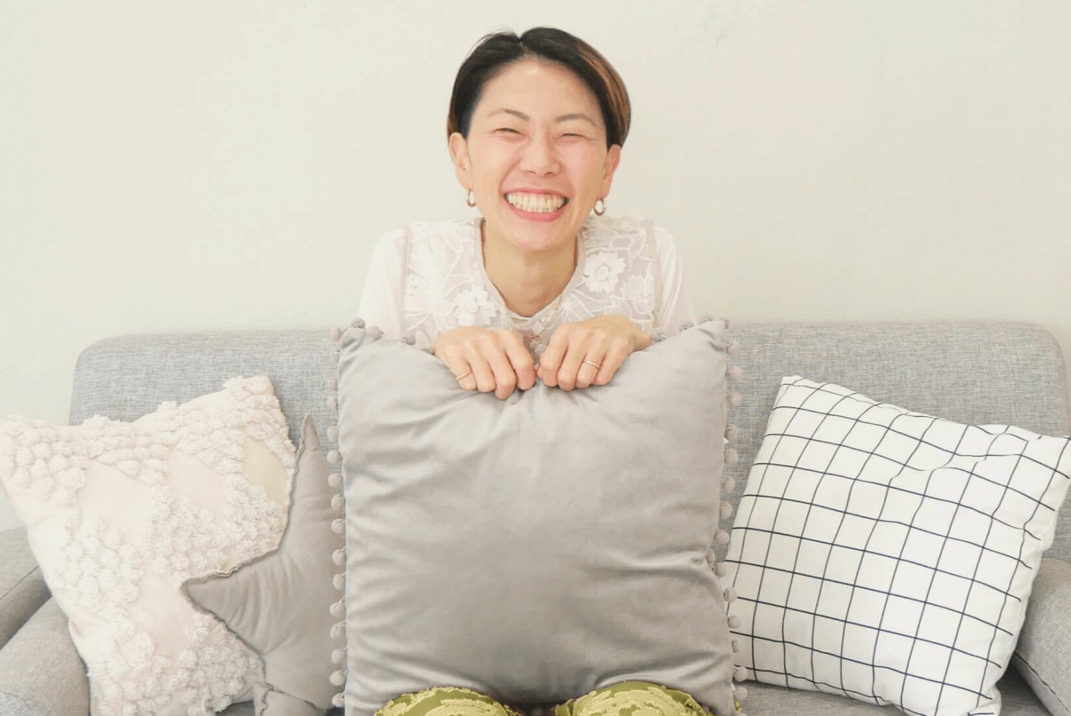 リビングのソファでクッションを抱え満面の笑みのtotoさん