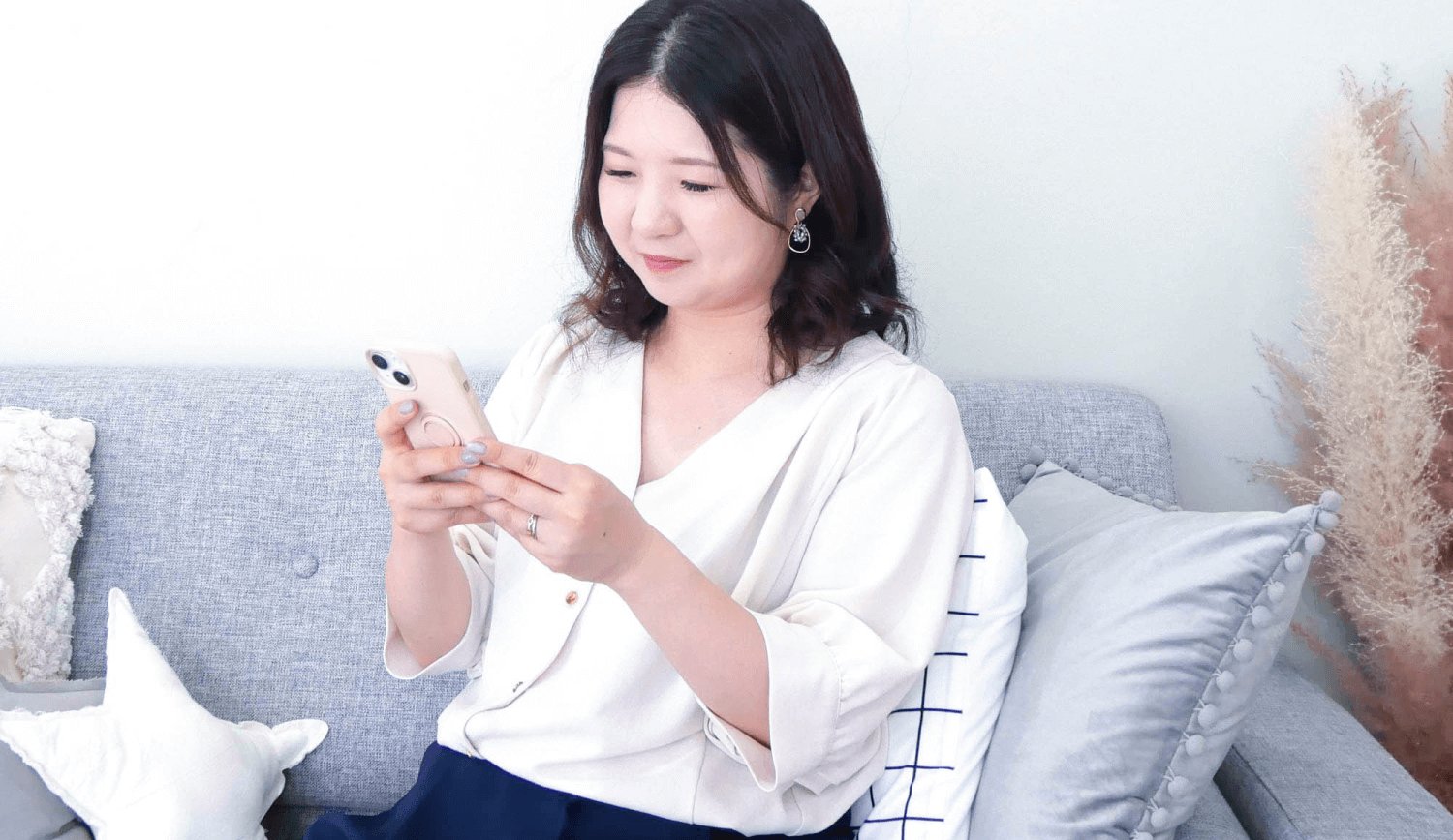 グレーのソファに座り、スマートフォンを操作するきなこさん
