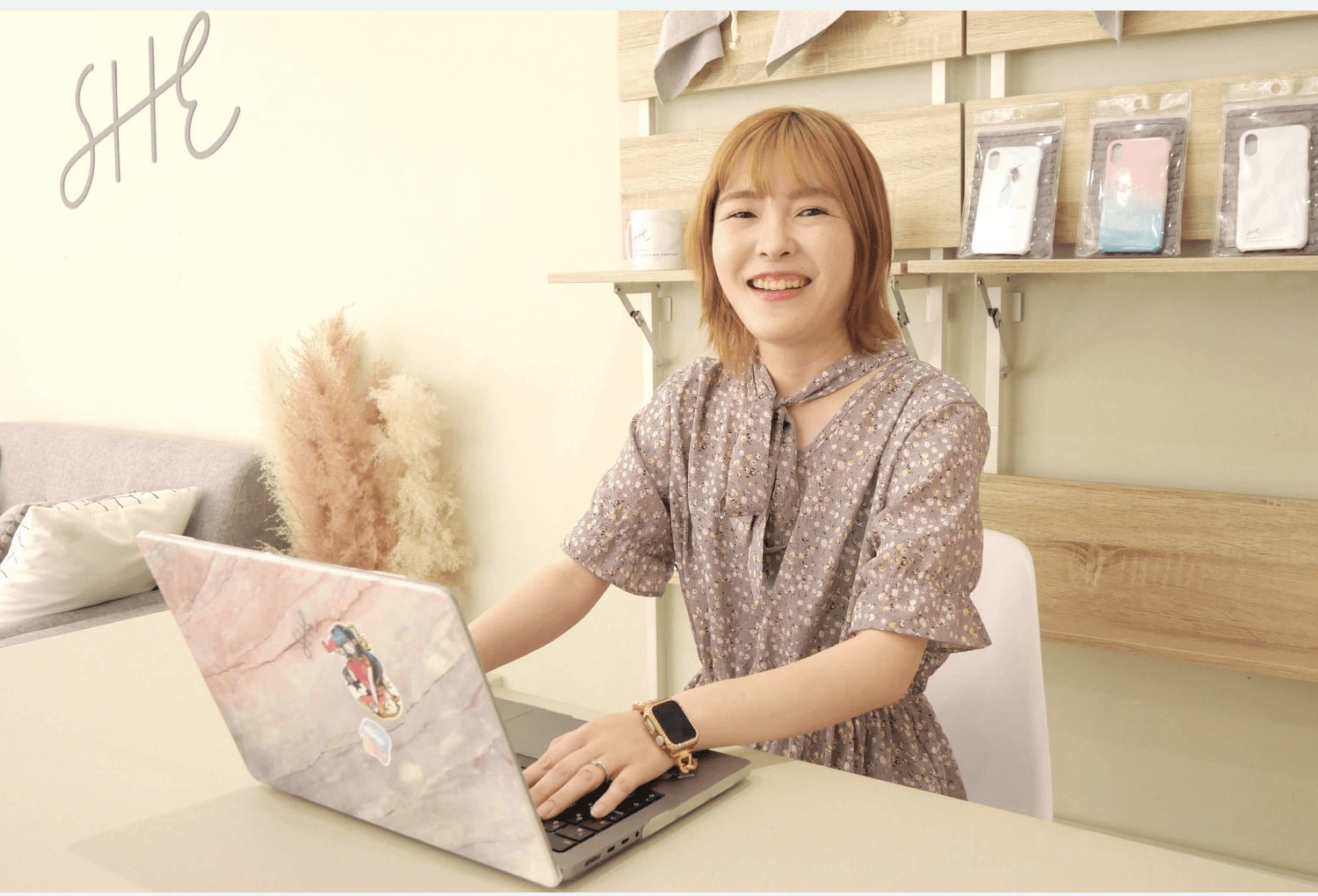 SHEのカフェスペースでノートPCに向かい微笑むmamiさん