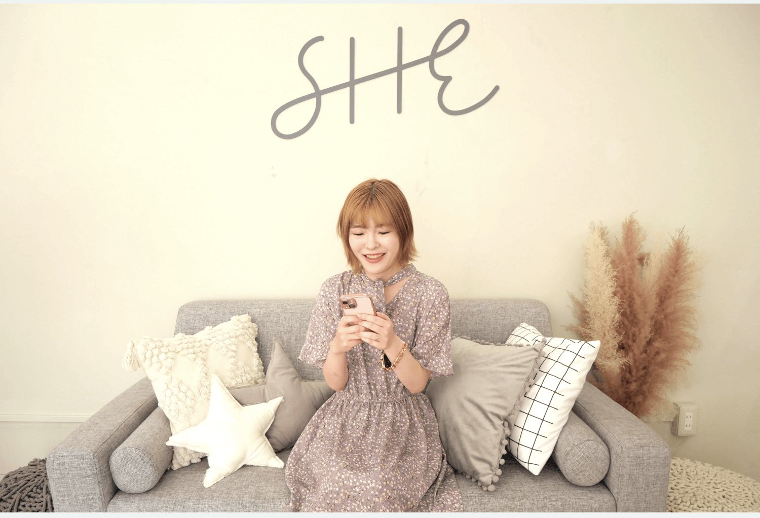 リビングのソファでスマホを見て微笑むmamiさん