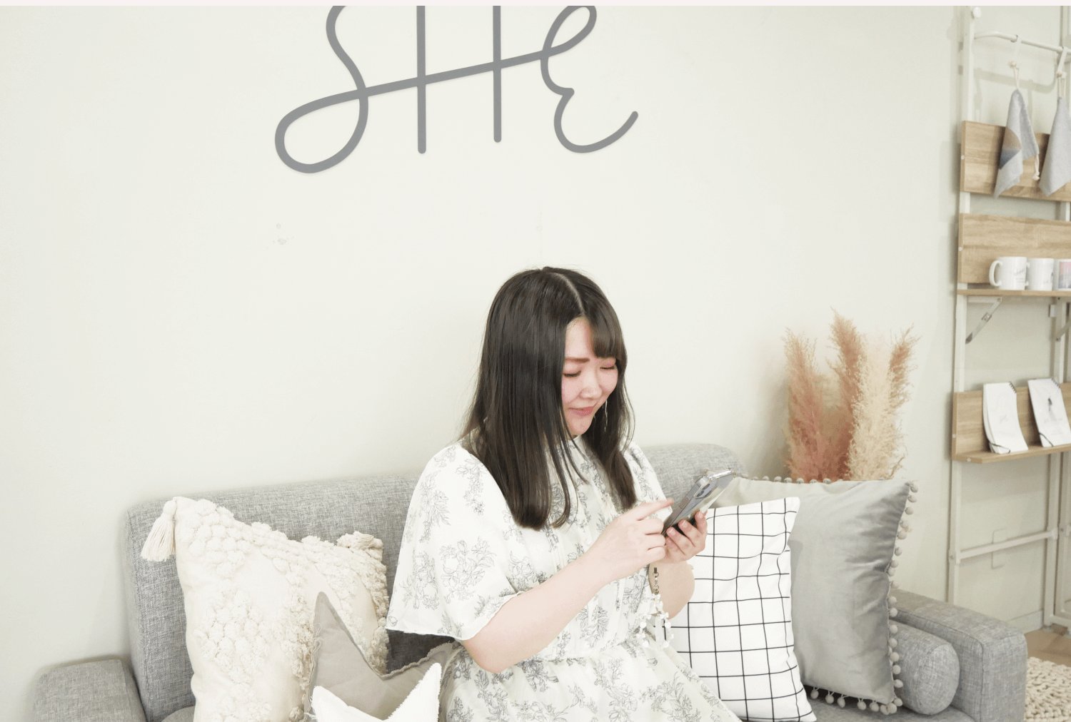 SHE拠点のソファでスマートフォンを操作しながら微笑むもかさん