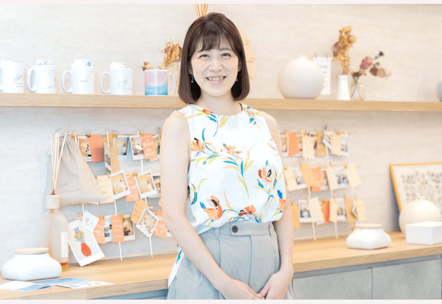 雑貨や陶器が並ぶ棚の前に立つしょこまるさん