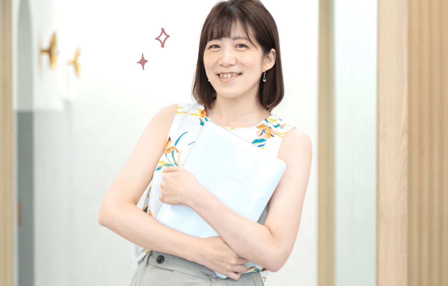 SHElikes拠点のエントランスで書類を抱えて微笑むしょこまるさん
