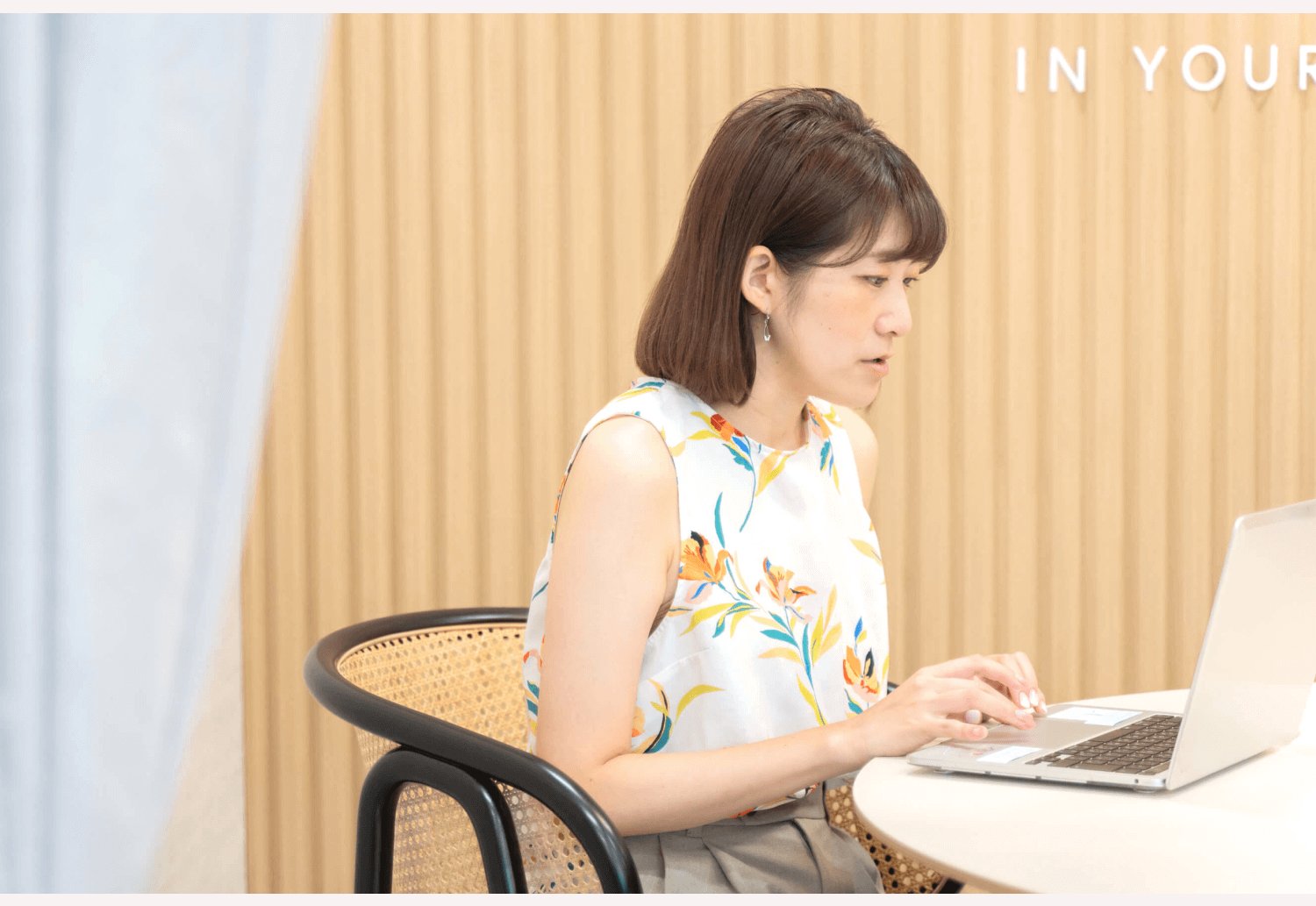 「IN YOUR」の壁面サイネージを背景に、PCに向かうしょこまるさん